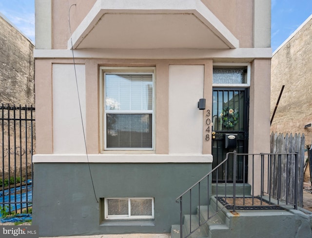 property entrance with fence and stucco siding