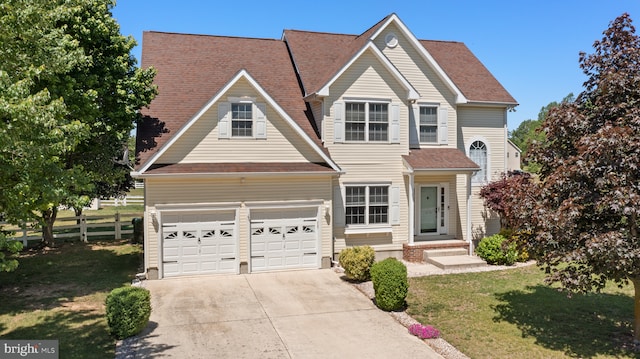 traditional-style home featuring driveway, an attached garage, and a shingled roof