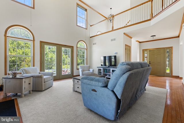 living area with a towering ceiling, french doors, hardwood / wood-style flooring, and baseboards