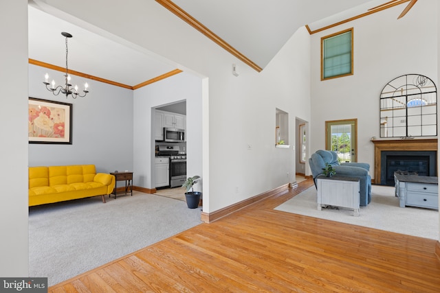 carpeted living area featuring crown molding, a chandelier, wood finished floors, baseboards, and a glass covered fireplace
