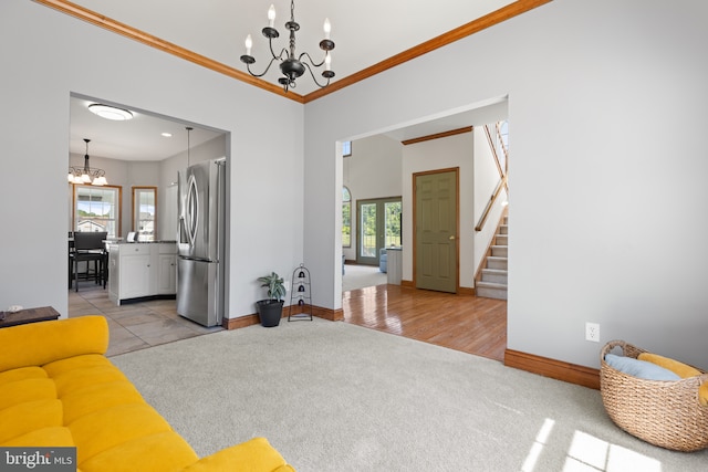 living room with a chandelier, light colored carpet, healthy amount of natural light, ornamental molding, and stairway