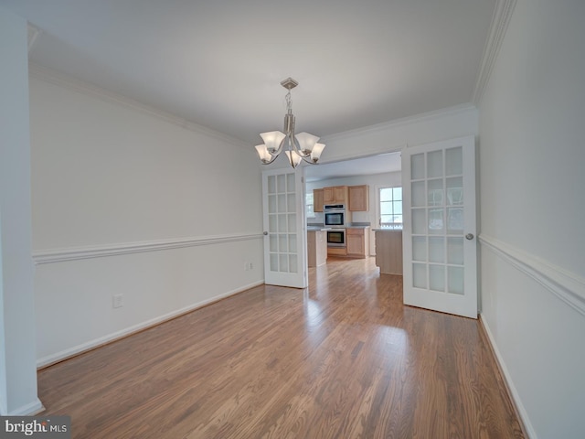 13195 Golders Green Pl, Bristow, VA 20136 - unfurnished dining area with french doors, a chandelier, wood finished floors, crown molding, and baseboards