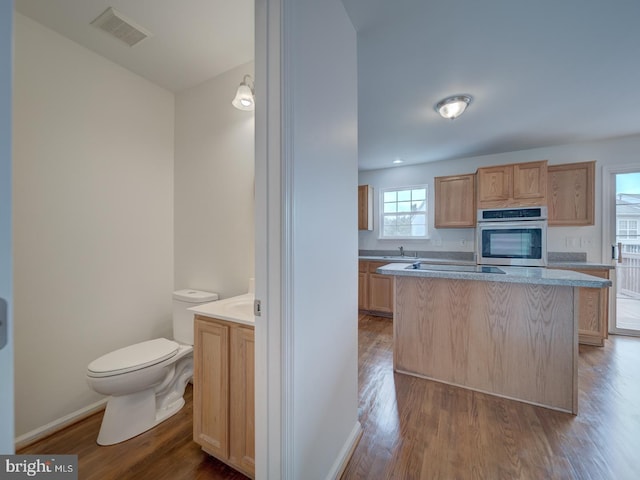 13195 Golders Green Pl, Bristow, VA 20136 - kitchen featuring stainless steel oven, wood finished floors, baseboards, and light brown cabinets