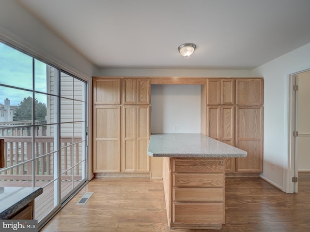 13195 Golders Green Pl, Bristow, VA 20136 - kitchen featuring light wood-type flooring, light brown cabinetry, baseboards, light stone countertops, and a center island