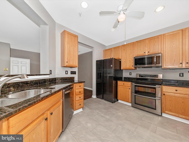 kitchen featuring stainless steel appliances, a sink, a ceiling fan, dark stone counters, and recessed lighting
