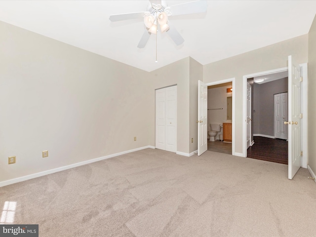 unfurnished bedroom with light colored carpet, baseboards, ensuite bathroom, and a ceiling fan