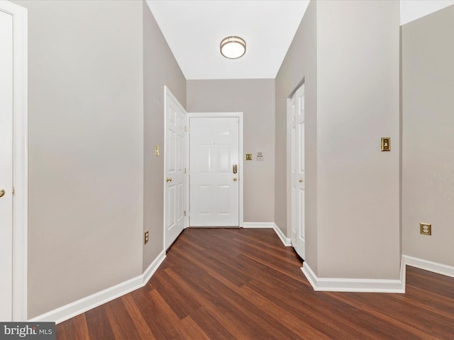 hallway featuring dark wood finished floors and baseboards