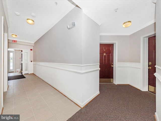 hallway featuring crown molding, wainscoting, and light tile patterned flooring