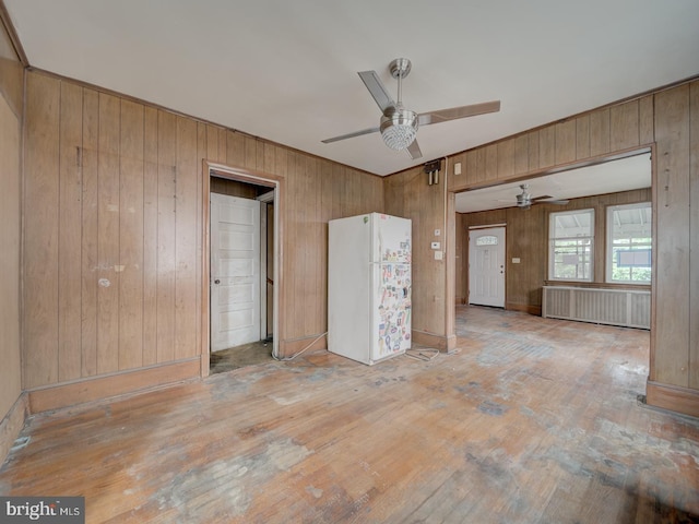 820 Tuckerman St NW, Washington, DC 20011 - spare room featuring radiator heating unit, a ceiling fan, wood walls, and light wood-style floors