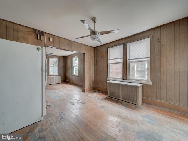 820 Tuckerman St NW, Washington, DC 20011 - spare room with radiator heating unit, a ceiling fan, light wood-type flooring, and wooden walls