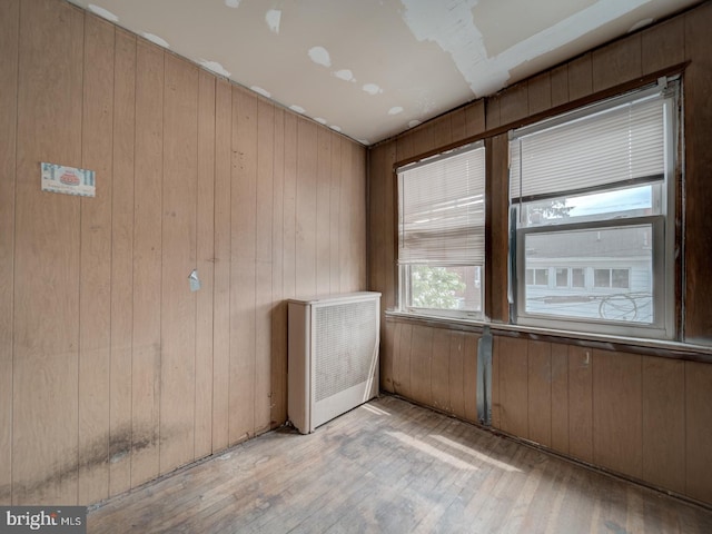 820 Tuckerman St NW, Washington, DC 20011 - unfurnished room featuring light wood finished floors, wood walls, and radiator heating unit