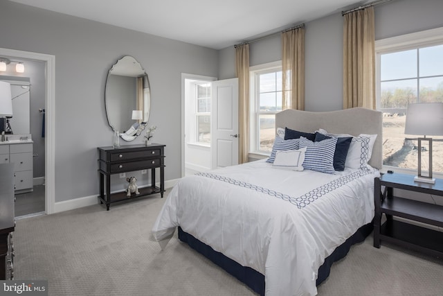 bedroom featuring light colored carpet, ensuite bathroom, and baseboards