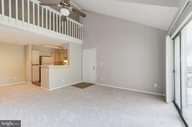 unfurnished living room with light carpet, a ceiling fan, high vaulted ceiling, and baseboards