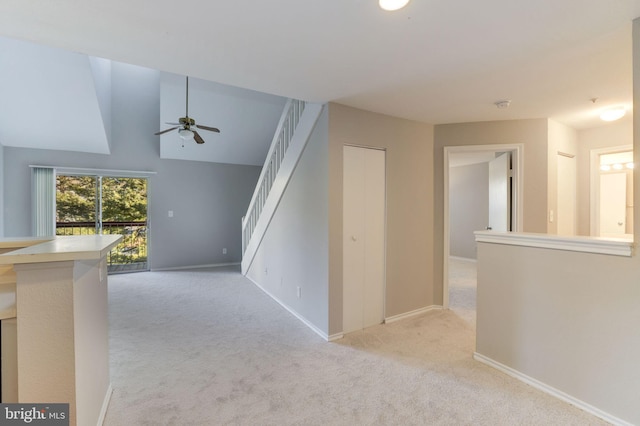 hall with light colored carpet, stairs, baseboards, and lofted ceiling