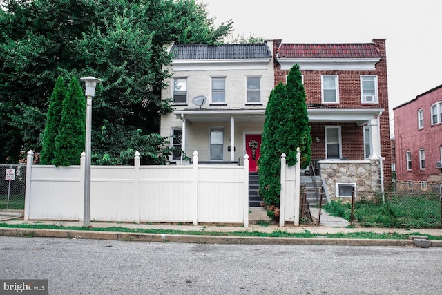 5519 Minnoka Ave, Baltimore, MD 21215 - townhome / multi-family property with a fenced front yard, brick siding, and covered porch