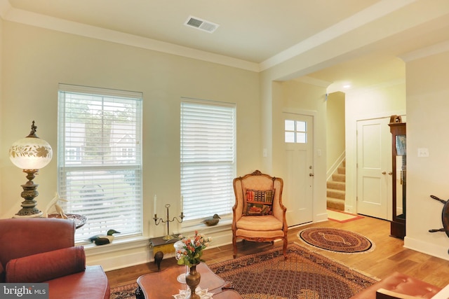 living area featuring wood finished floors, stairway, ornamental molding, and baseboards