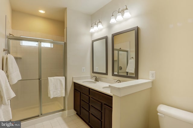 bathroom featuring toilet, a shower stall, tile patterned floors, and double vanity