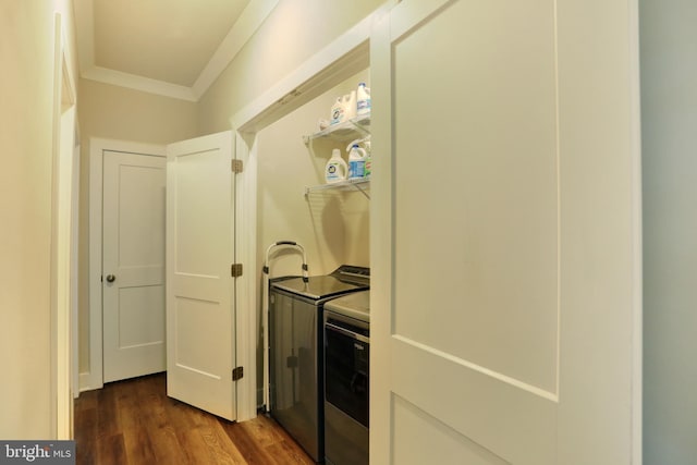 laundry room featuring dark wood finished floors, washing machine and dryer, and crown molding