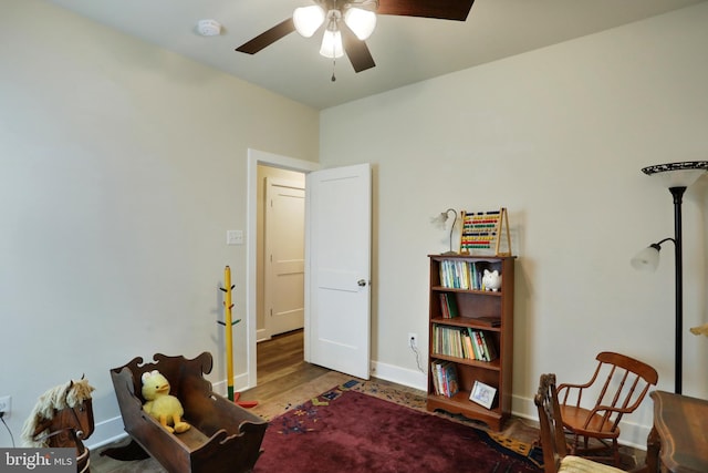 living area featuring ceiling fan, baseboards, and wood finished floors