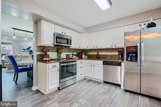 kitchen with appliances with stainless steel finishes, light wood finished floors, white cabinets, and a sink