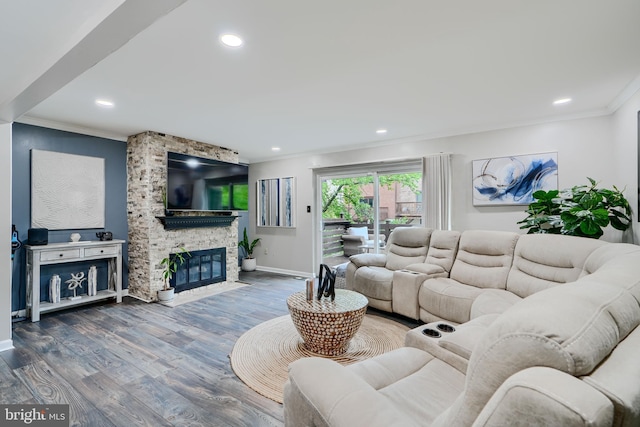 living room with crown molding, wood finished floors, baseboards, recessed lighting, and a stone fireplace
