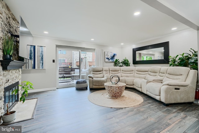living room featuring a fireplace, ornamental molding, wood finished floors, baseboards, and recessed lighting