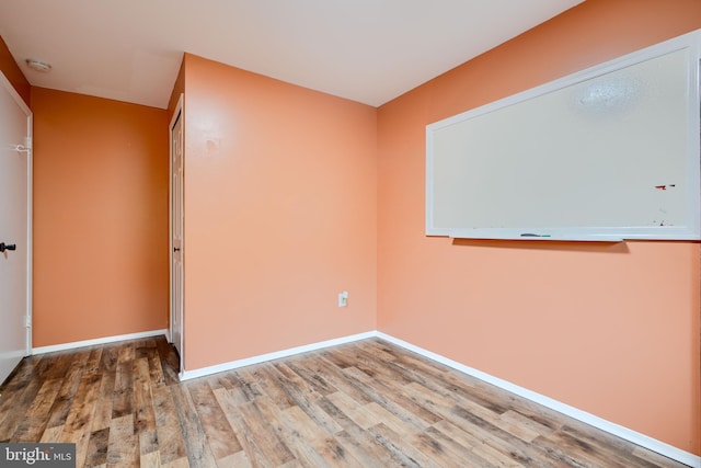 unfurnished room with wood finished floors, baseboards, and a smoke detector