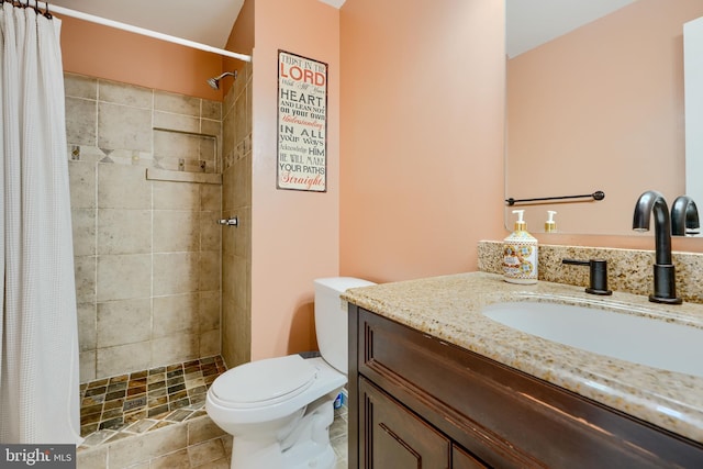 full bathroom with vanity, a tile shower, and toilet