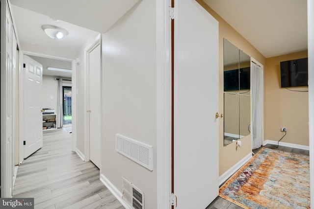 corridor featuring light wood-style floors and baseboards