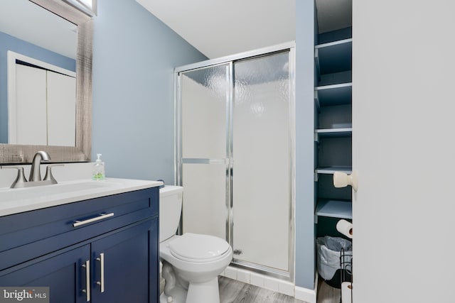 full bathroom with a stall shower, toilet, wood finished floors, and vanity
