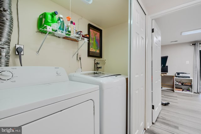 laundry area with washing machine and dryer and light wood-style flooring