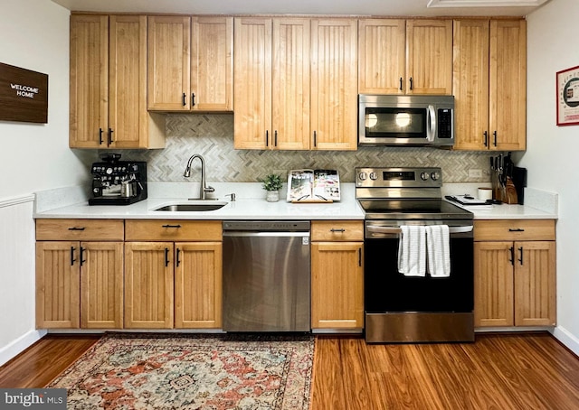 kitchen with stainless steel appliances, a sink, light countertops, and dark wood finished floors