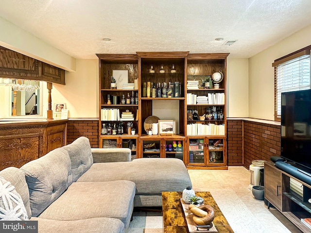 living area featuring a textured ceiling and wainscoting