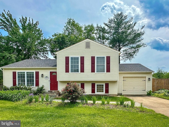 split level home featuring concrete driveway, an attached garage, and a shingled roof