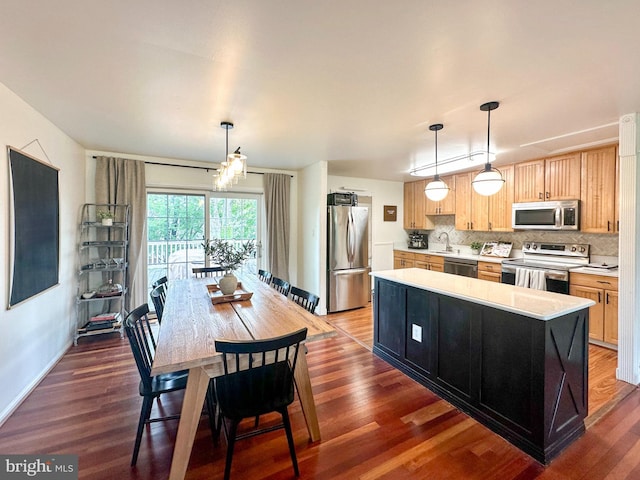 kitchen featuring stainless steel appliances, a sink, light brown cabinets, wood finished floors, and light countertops