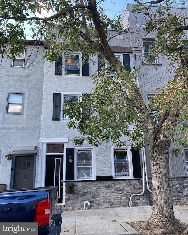 view of property featuring stucco siding and stone siding