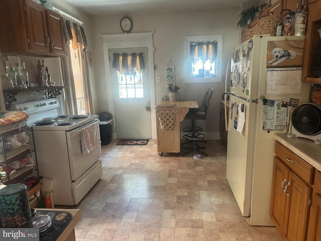 kitchen with white appliances, plenty of natural light, light countertops, and stone finish floors
