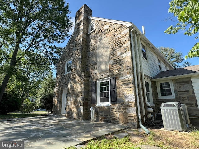 615 Bryn Mawr Ave, Penn Valley, PA 19072 - view of side of home featuring stone siding, cooling unit, a chimney, and a patio