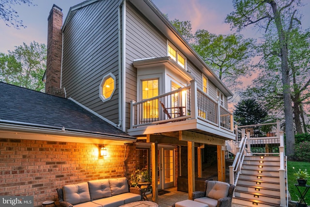 8412 Riverside Rd, Alexandria, VA 22308 - back of property at dusk featuring outdoor lounge area, a wooden deck, stairs, a chimney, and a shingled roof