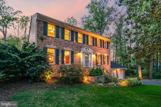 8412 Riverside Rd, Alexandria, VA 22308 - view of front facade featuring a garage, a lawn, a chimney, brick siding, and asphalt driveway