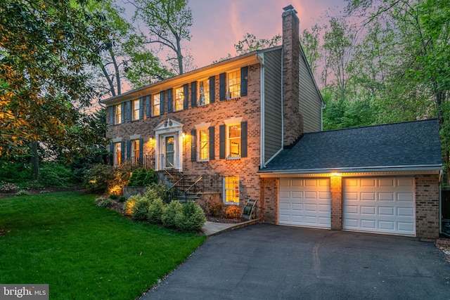 8412 Riverside Rd, Alexandria, VA 22308 - colonial home with a chimney, an attached garage, driveway, brick siding, and a lawn