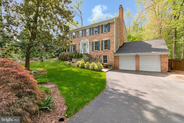 8412 Riverside Rd, Alexandria, VA 22308 - colonial-style house featuring a chimney, asphalt driveway, a garage, and brick siding