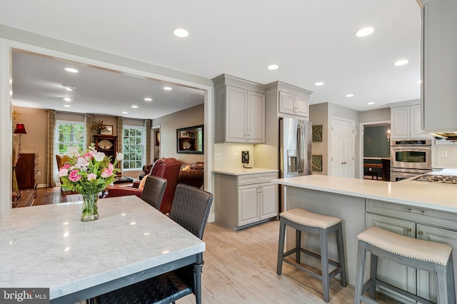 8412 Riverside Rd, Alexandria, VA 22308 - kitchen featuring stainless steel appliances, gray cabinetry, light wood-type flooring, recessed lighting, and a kitchen breakfast bar