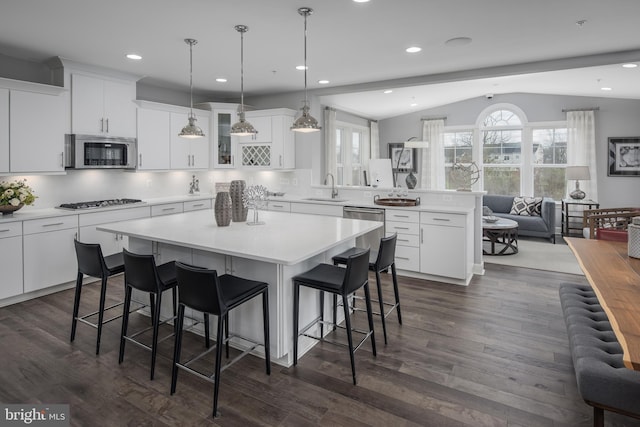 kitchen featuring stainless steel appliances, a sink, a peninsula, lofted ceiling, and open floor plan