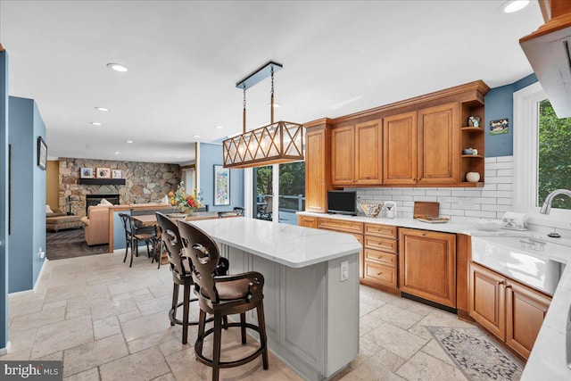 kitchen with a sink, stone tile floors, recessed lighting, brown cabinets, and a kitchen island