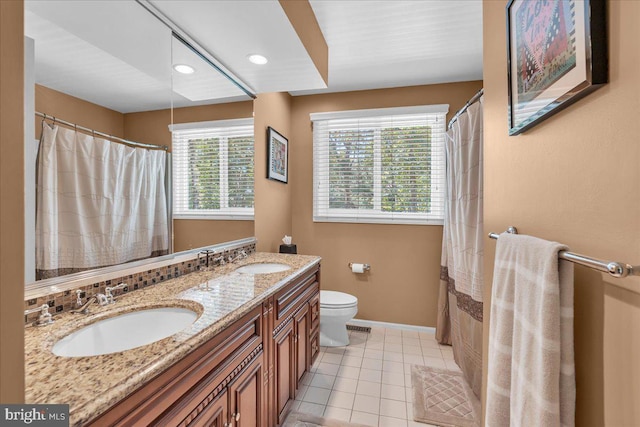 bathroom with tile patterned flooring, toilet, baseboards, double vanity, and recessed lighting