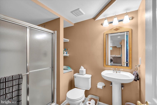 bathroom with a shower stall, toilet, and a sink