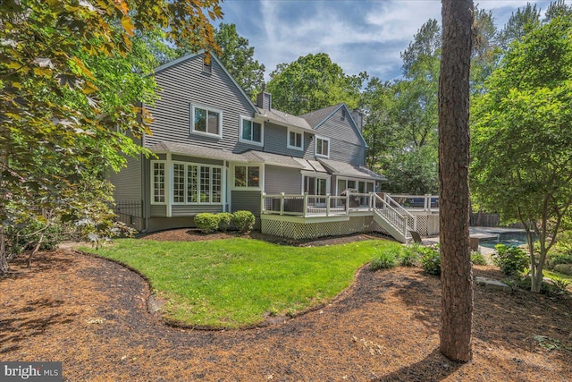 back of property featuring a wooden deck, a chimney, and a shingled roof