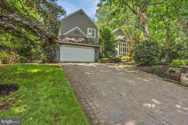 view of front of home with a garage, decorative driveway, and a front yard