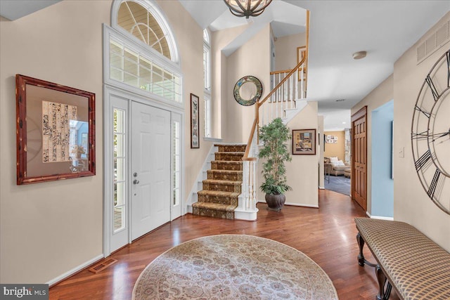 foyer entrance featuring stairway, wood finished floors, baseboards, and a high ceiling